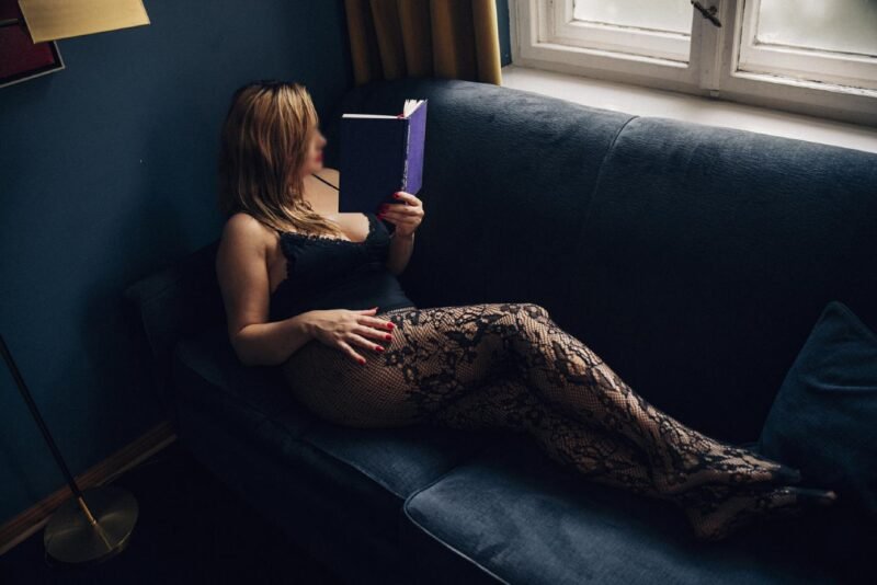 Model zeigt sich mit einem Buch, auf der Couch.