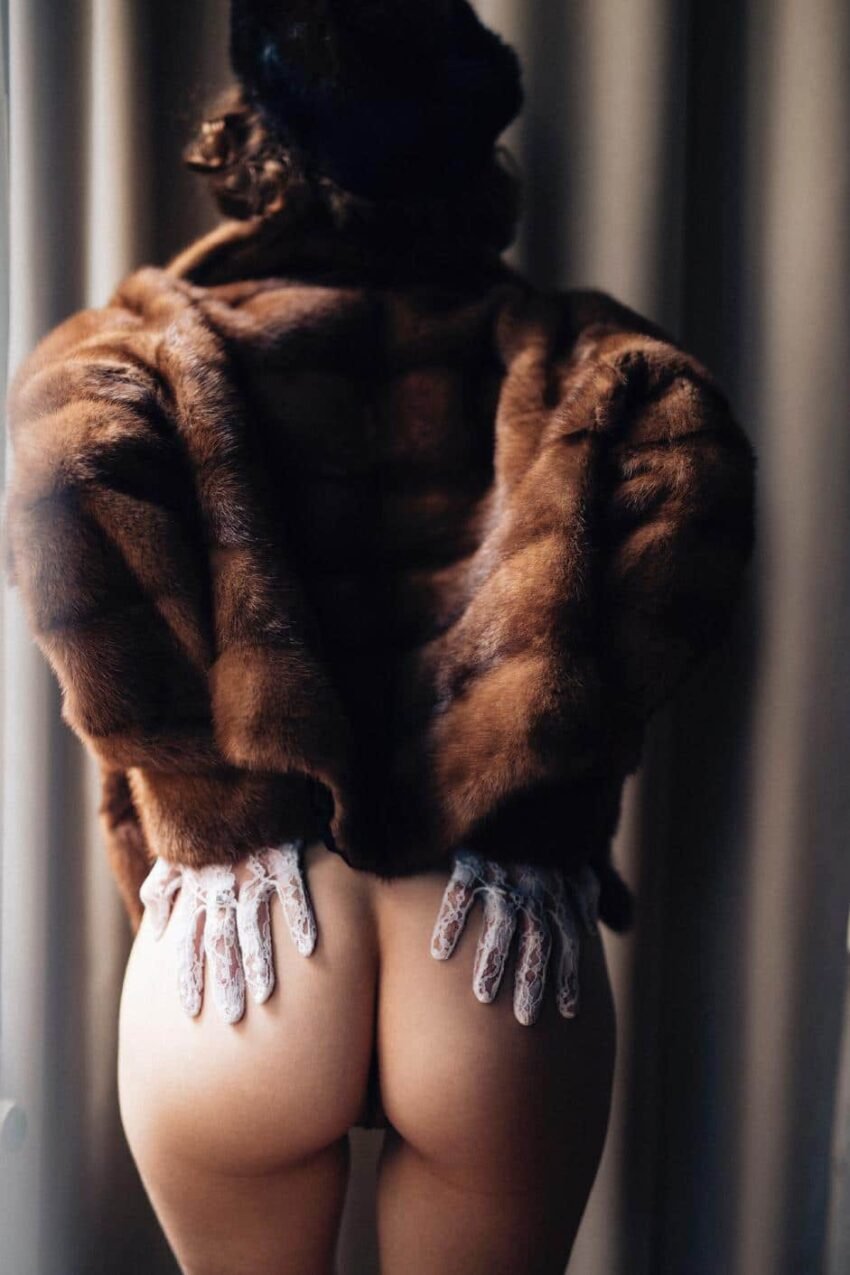 Das Bild zeigt das Model mit ihrem nackten Po, gekleidet in Pelz und Handschuhen.