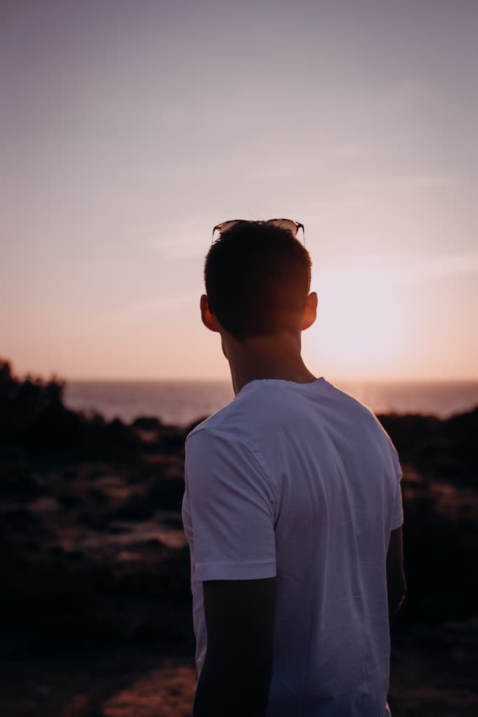 Das Bild zeigt einen jungen Mann im Abendlicht am Strand.