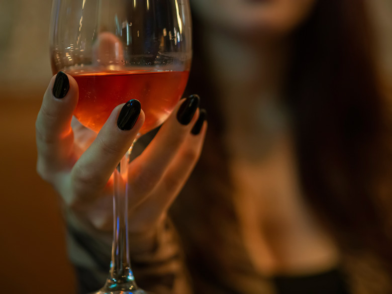 Das Bild zeigt eine Frau mit einem Glas Wein in der Hand und dient als Titelbild für das Thema „Die verschiedenen Arten des Begleitservices reichen von einer hübschen Abendbegleitung bis zu hemmungslosem Sex“.