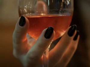 Das Foto zeigt eine Hand, die ein Weinglas hält.